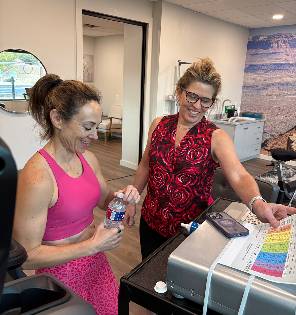 Two women standing in a room looking at a computer screen.