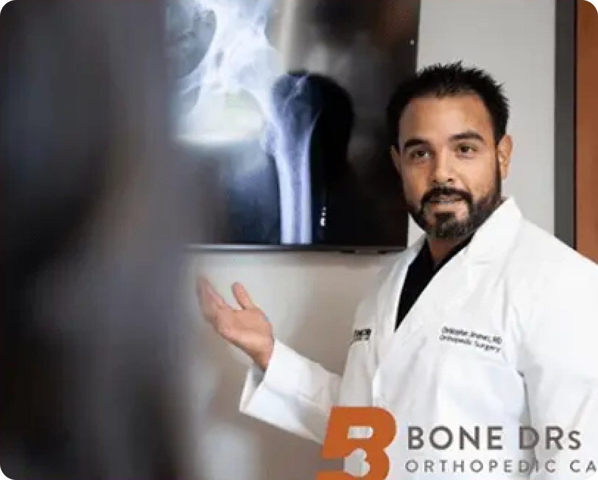 A man in a lab coat standing in front of a tv.