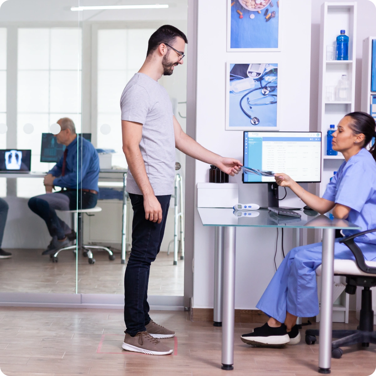 A man standing at a desk in front of a monitor.