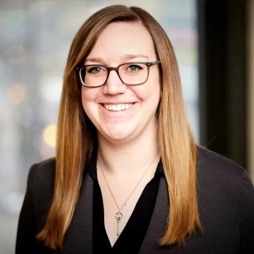 Jenny Lacey, woman with long red hair in a black blazer.