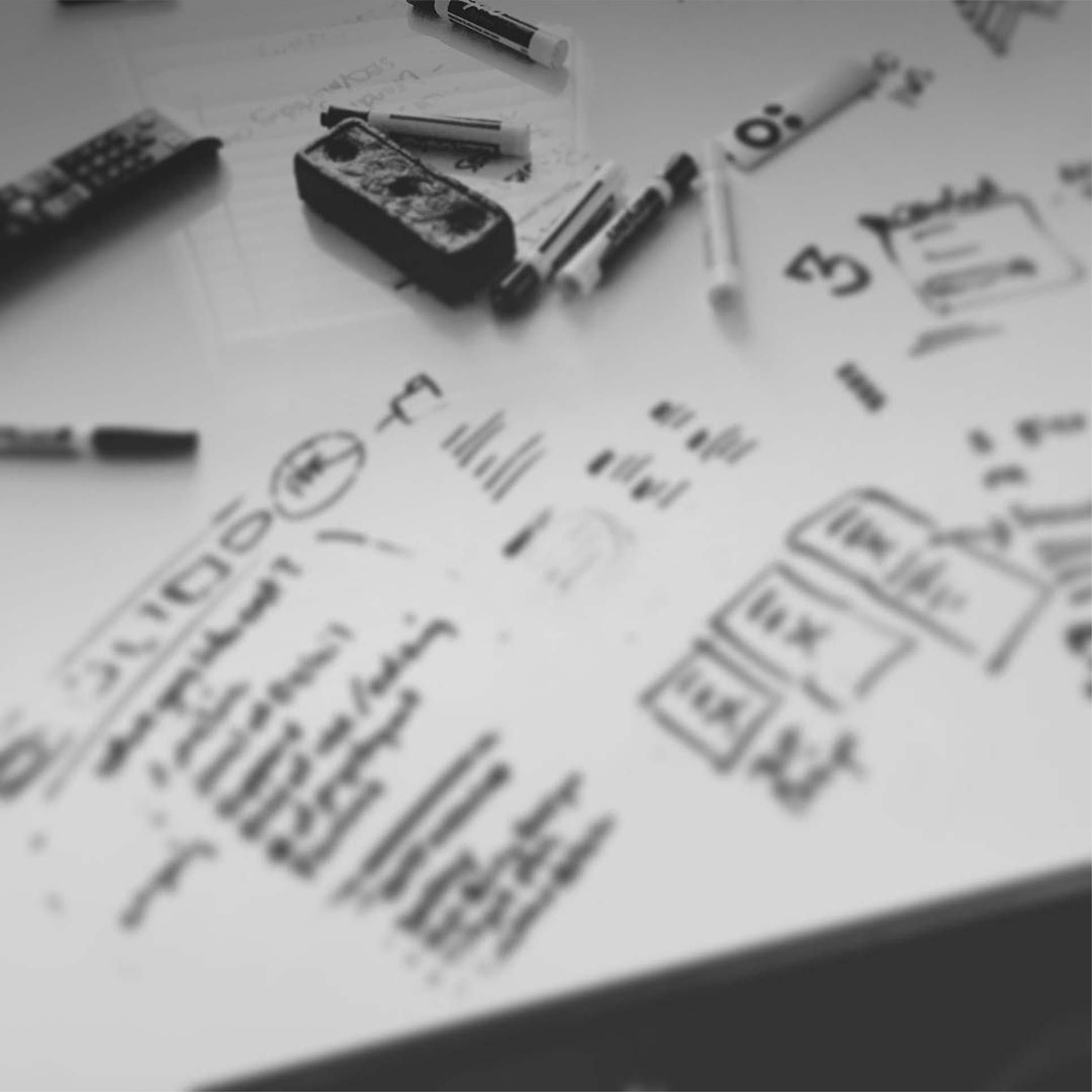 A whiteboard with handwritten notes, diagrams, and several markers on top.