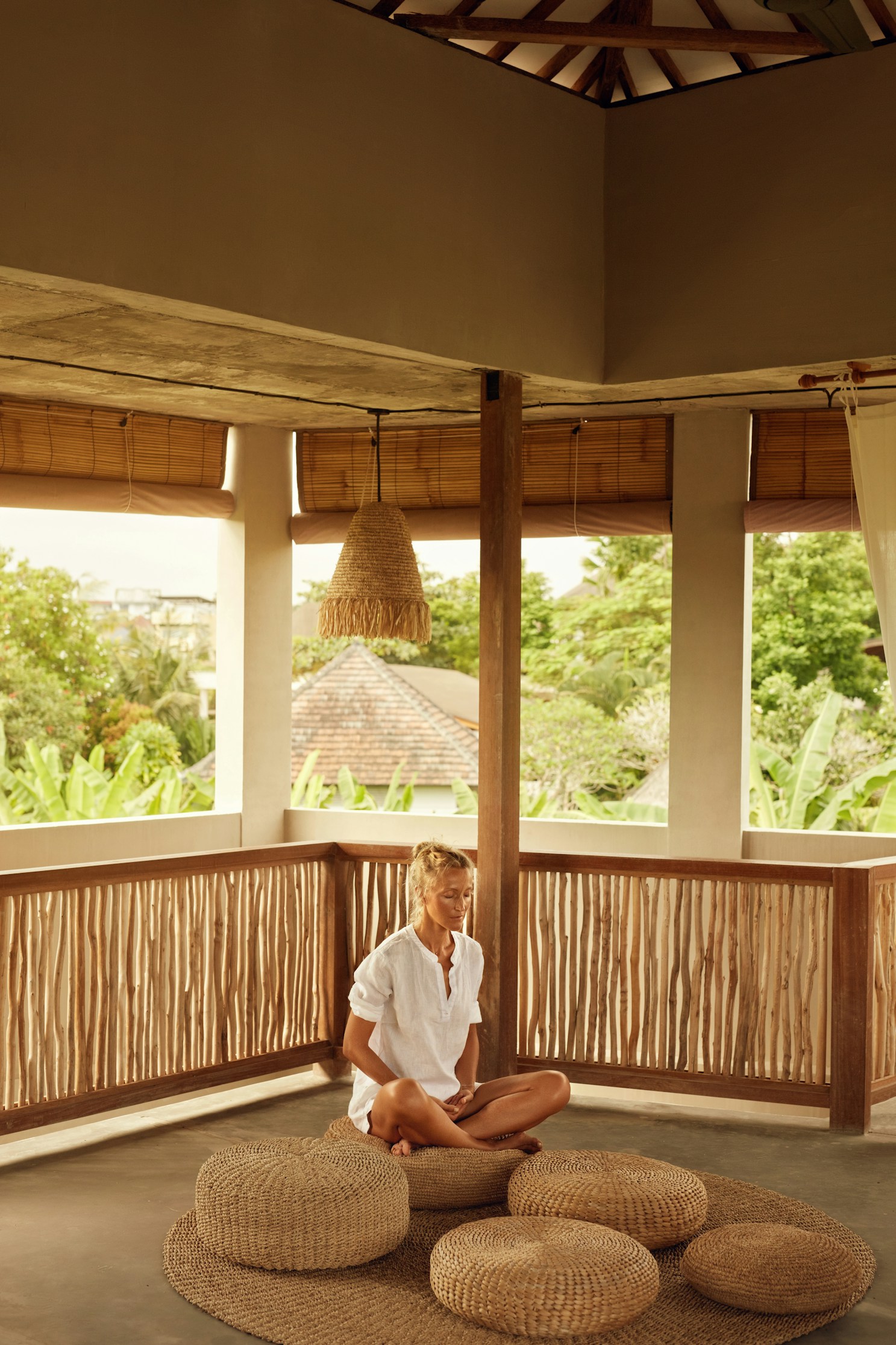 Woman in lotus position among woven cushions
