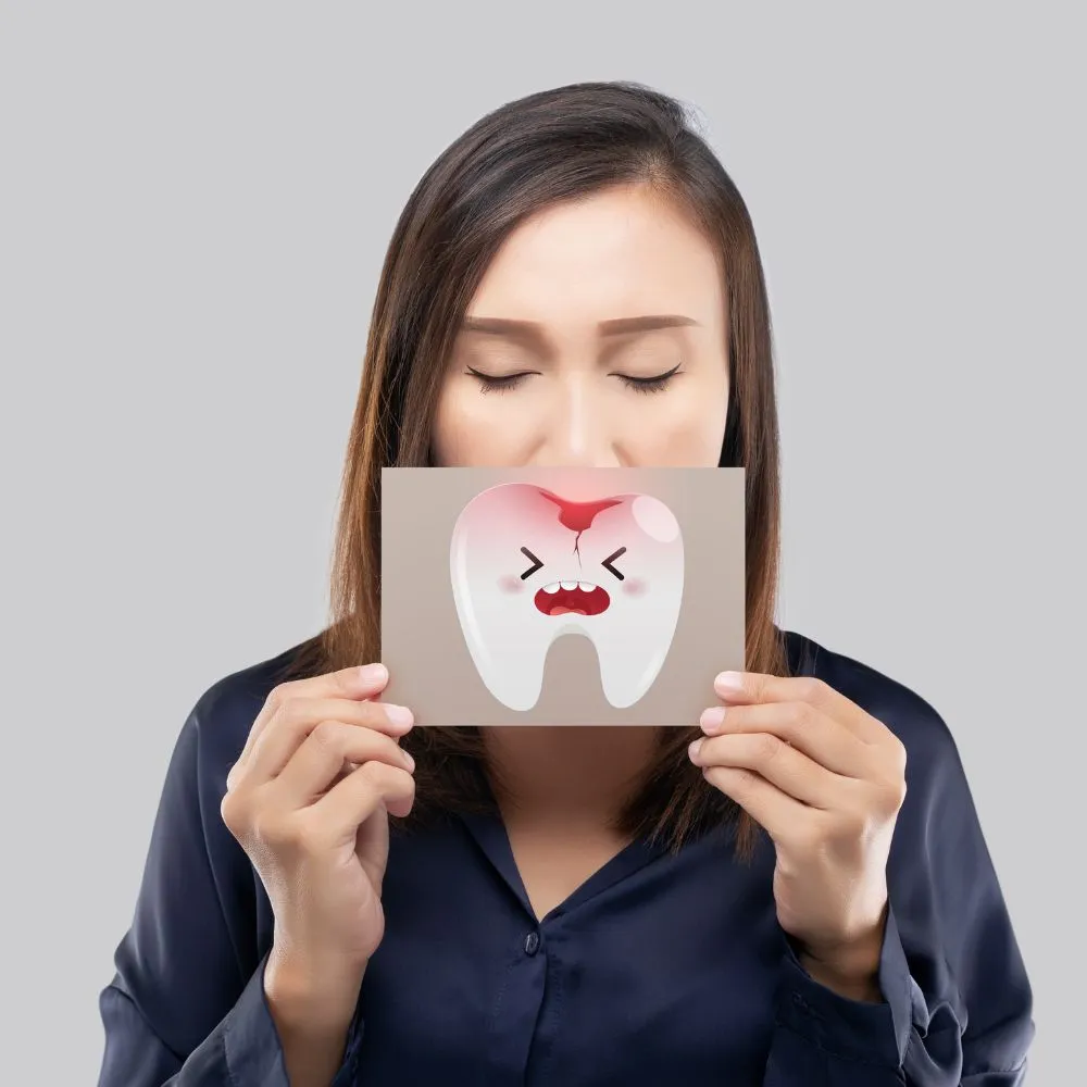 A woman holding a drawing of an inflamed tooth and gums in front of her mouth, symbolizing gum disease or periodontal issues.