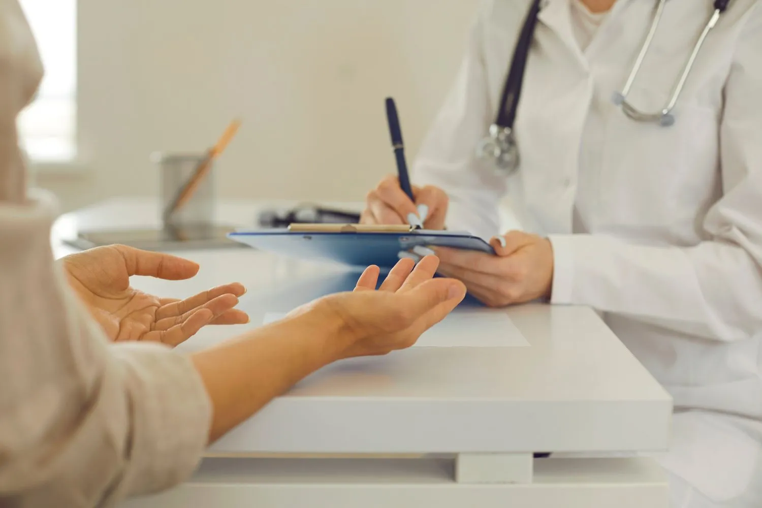 Close-up of a doctor writing on a clipboard while consulting a patient, symbolizing treatment planning or dental case documentation.