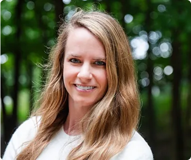 Smiling professional woman in white shirt against blurred green revLogic background