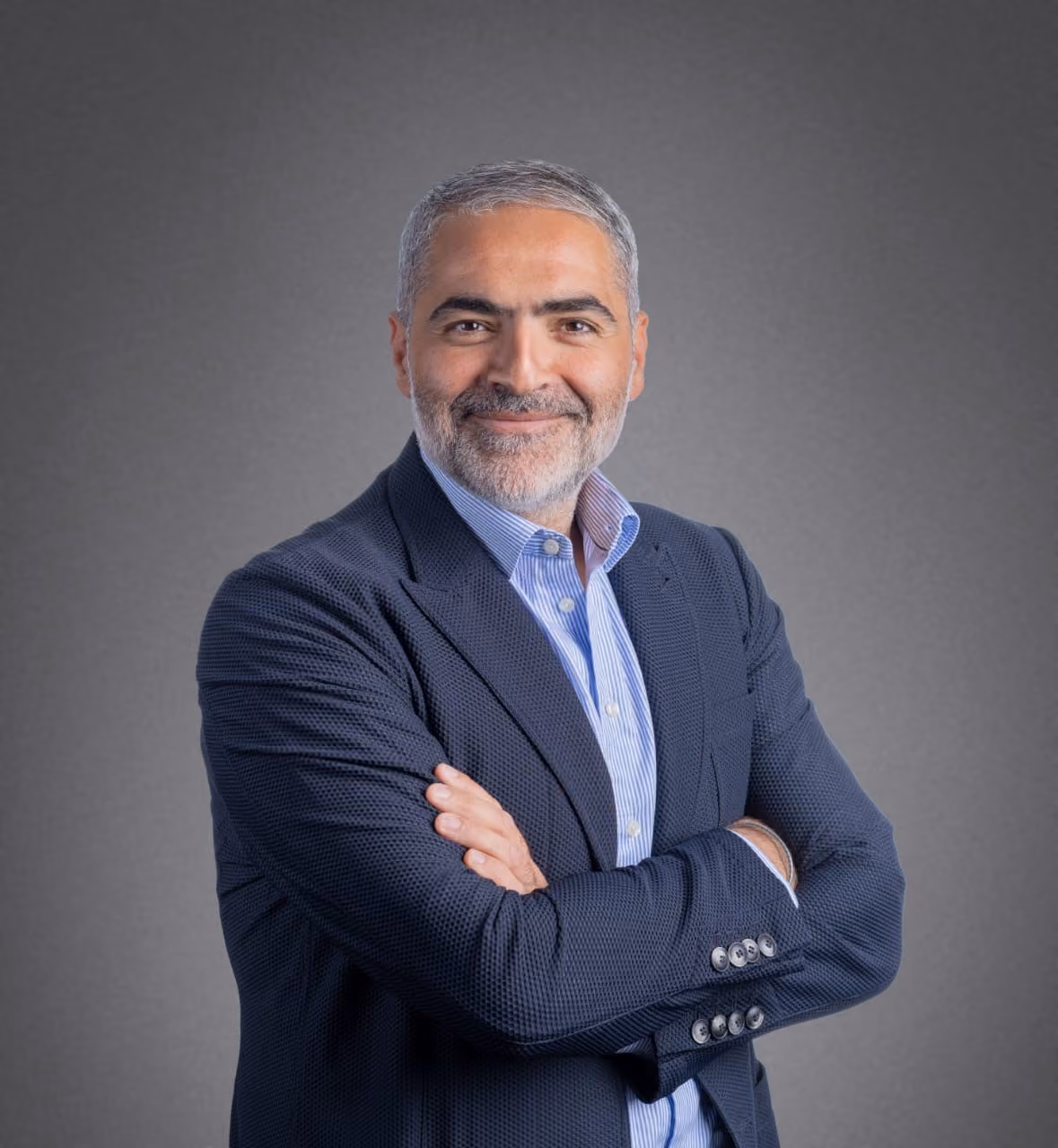 A person in a suit with his arms crossedDescription automatically generated, Picture
