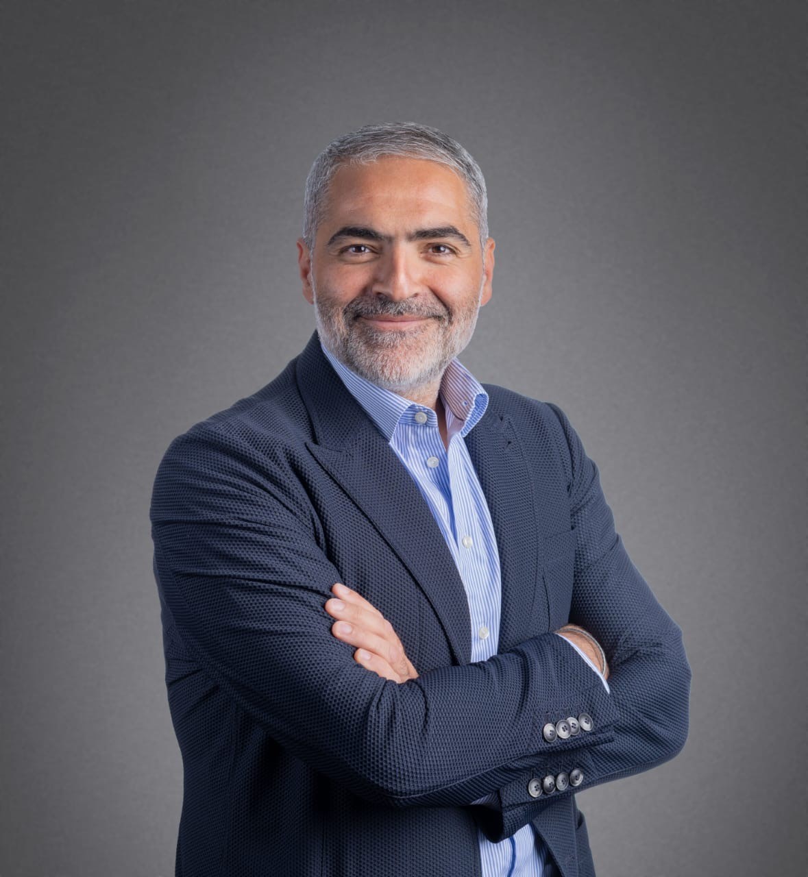 A person in a suit with his arms crossedDescription automatically generated, Picture