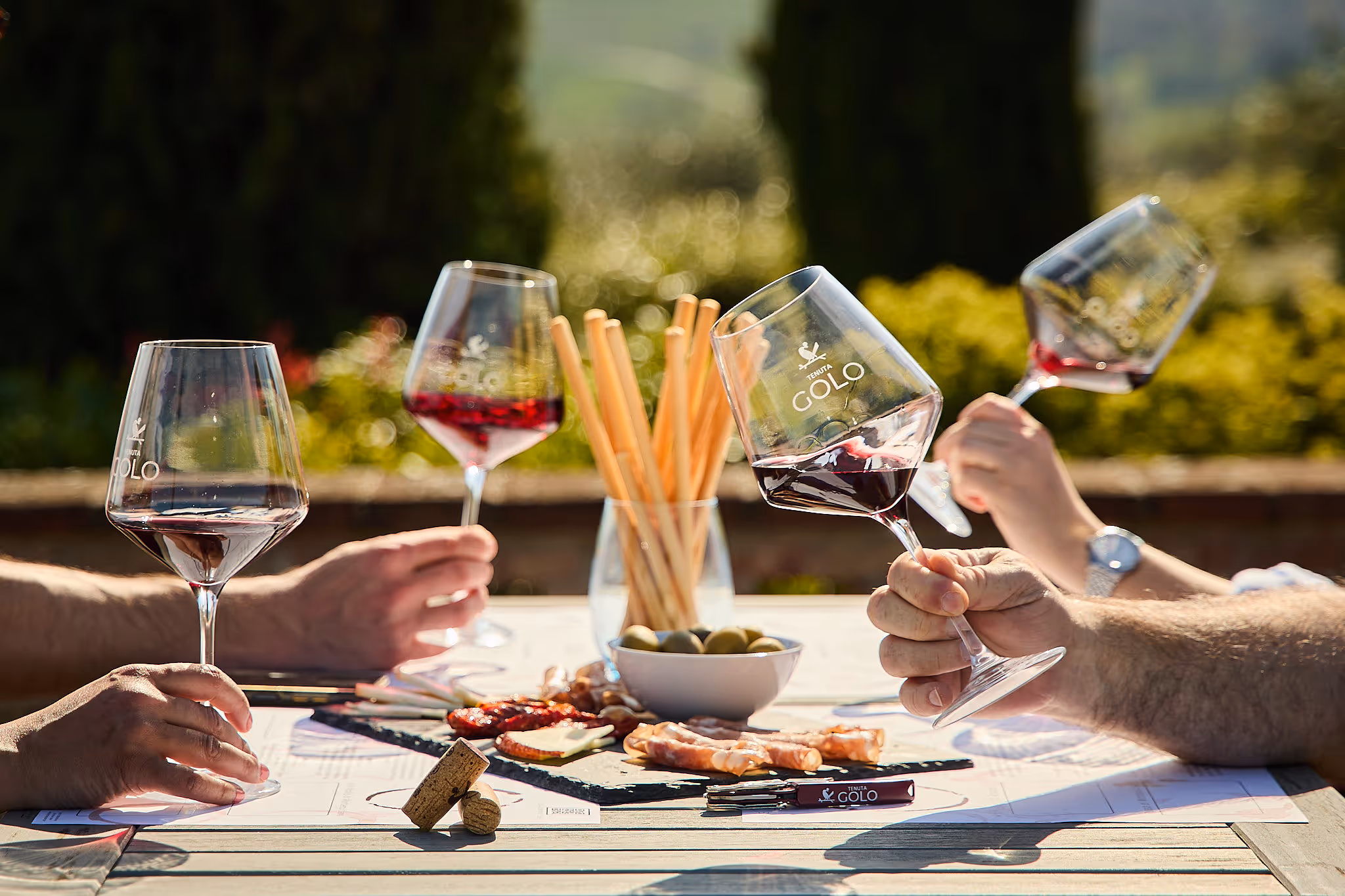 Guests enjoying a relaxed wine tasting at a Montepulciano winery, with glasses of red wine paired with a rustic Italian cheese and charcuterie platter featuring local salumi and aged pecorino.