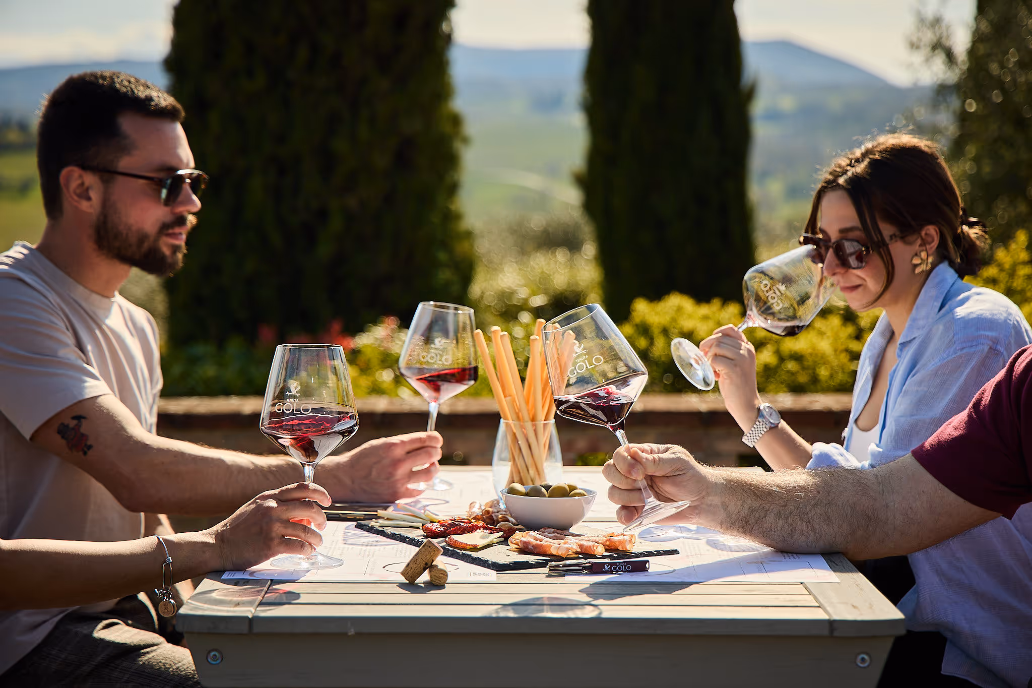 A small group of guests enjoying a relaxed wine tasting at a Montepulciano winery, chatting with the host and savoring local wines in a welcoming setting.