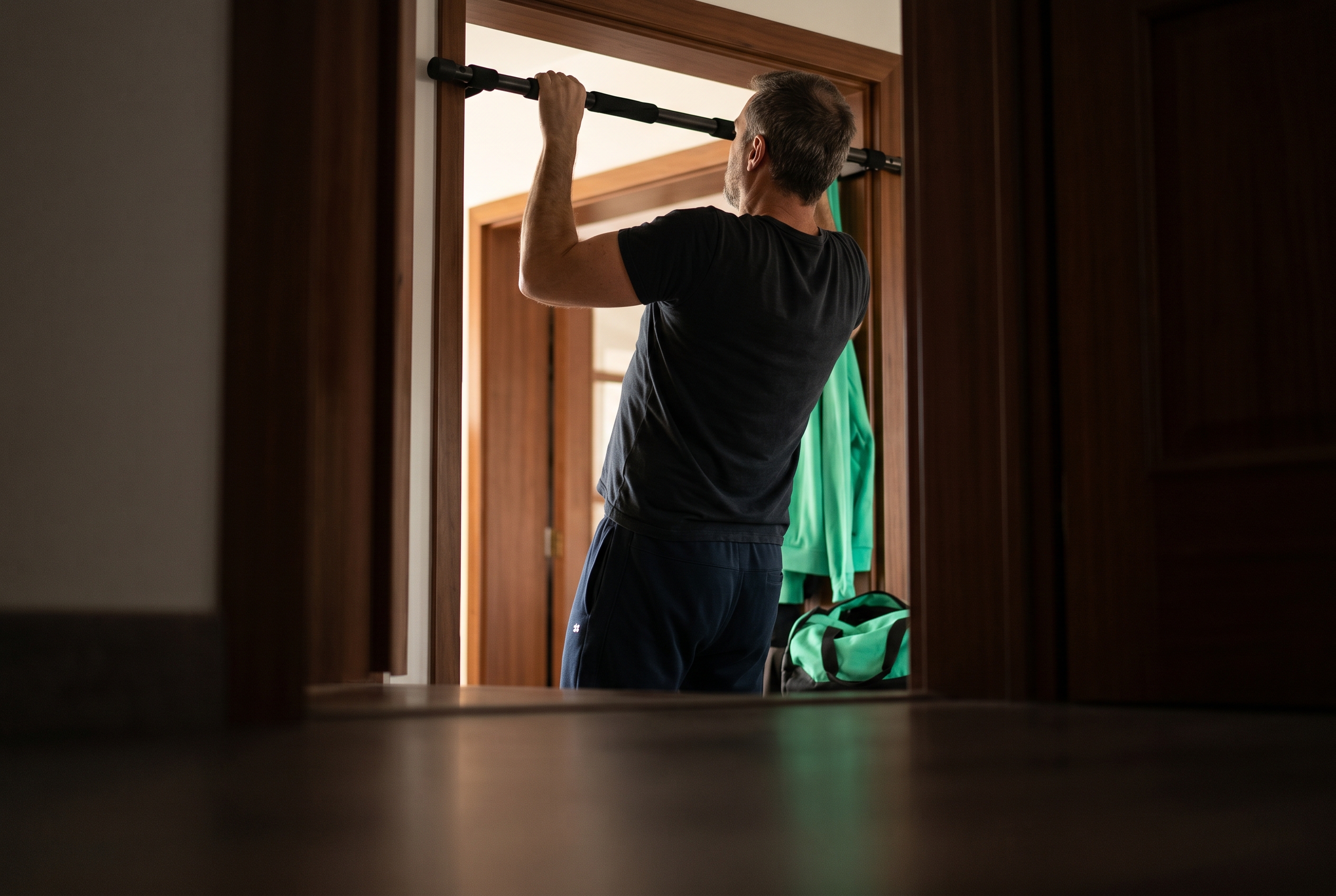 Homme qui fait des tractions sur une barre de porte, à la maison