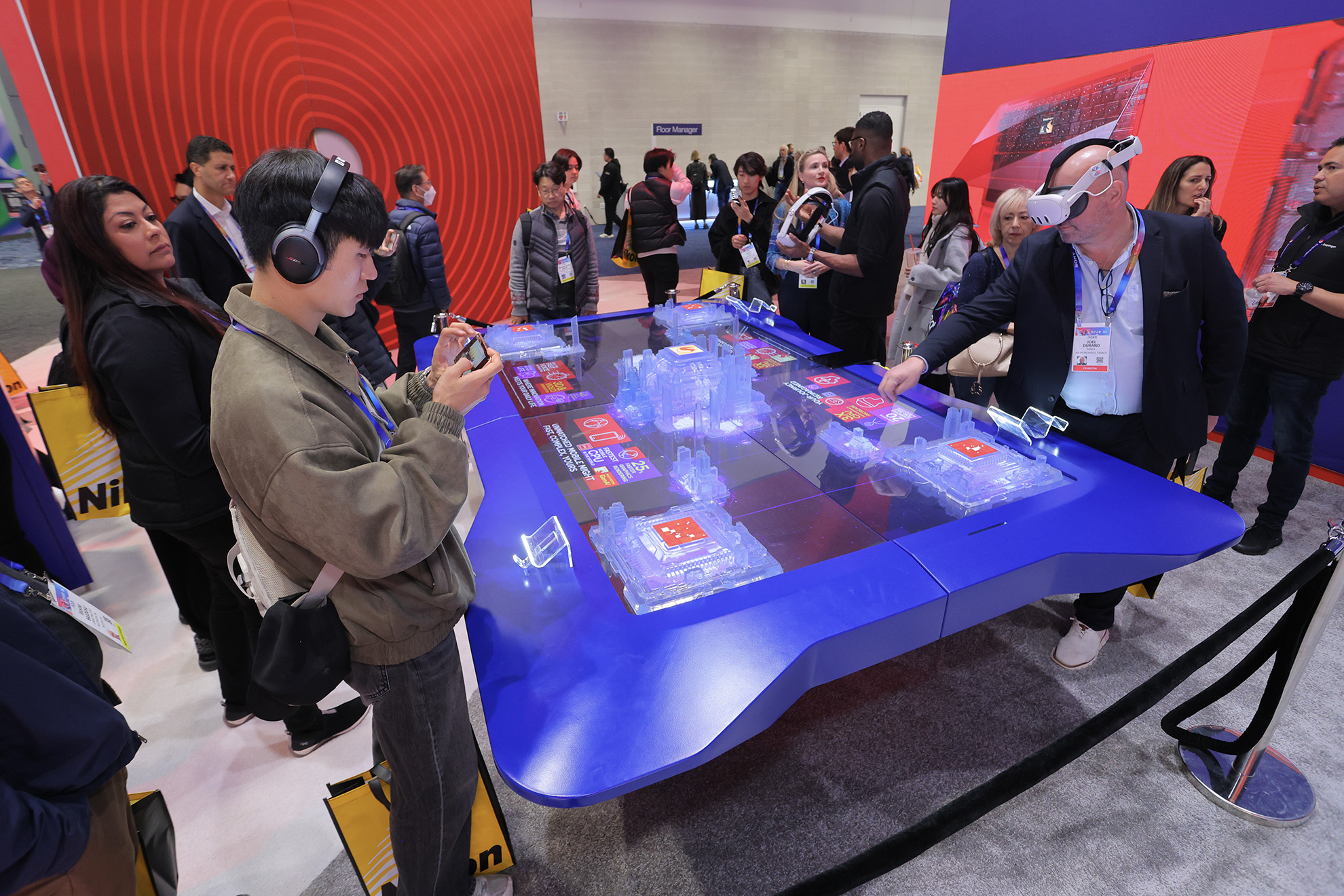 People interacting with technology at CES 2025, including VR headsets and interactive displays.