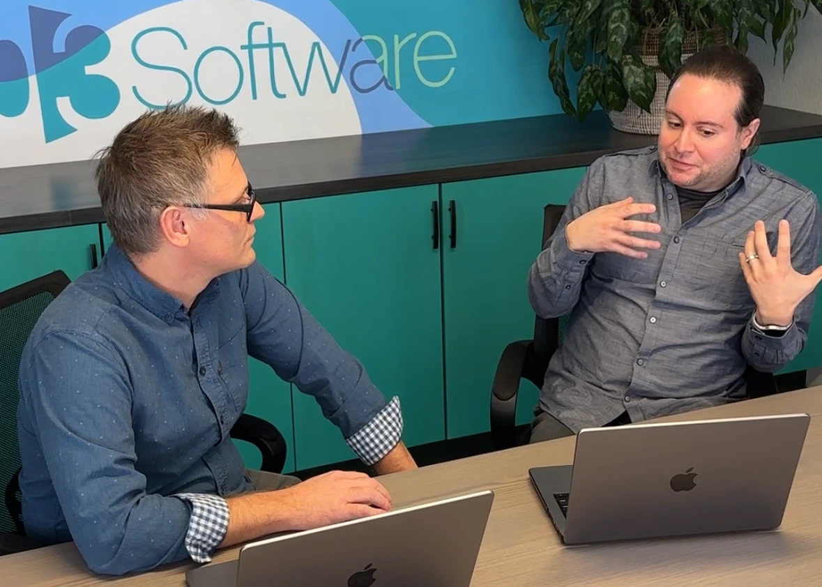 Fractional CTO and company CTO reviewing a software roadmap and delivery metrics at a conference table with laptops at 303 Software.