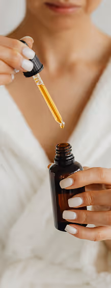 A woman holding an dropper above a bottle of serum