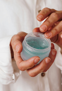 A close-up of a person's hand holding face cream, about to take some face cream with their finger