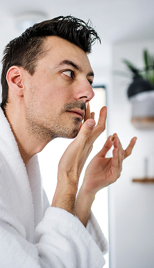 A man looking at a mirror applying cream to their face