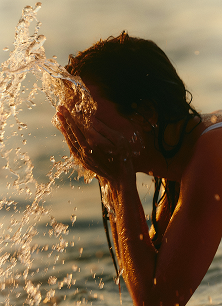 A person washing their face in the ocean