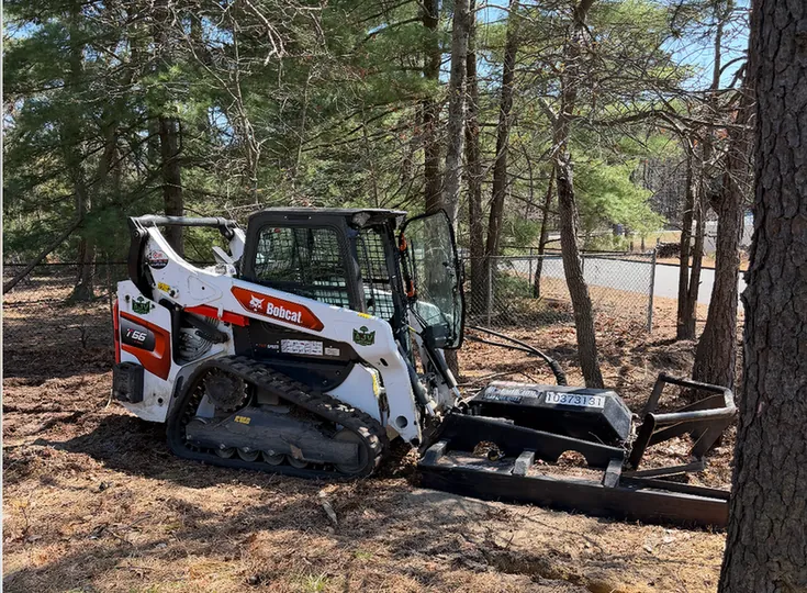 A tracked loader with a clearing attachment shows excavation site preparation by AJV Landscape, based in Toms River NJ.