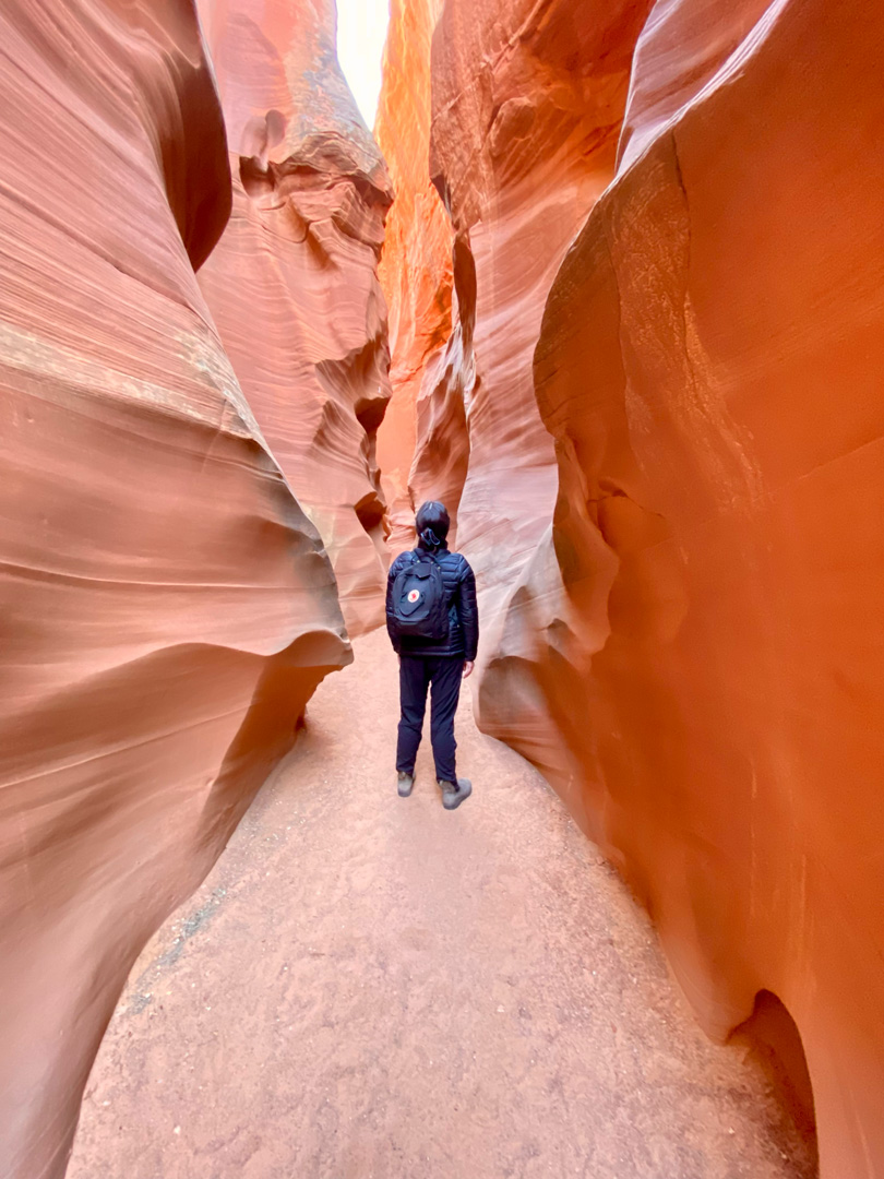 Traveler with a backpack walking through the narrow red sandstone walls of Antelope Canyon in Arizona, experiencing the natural beauty and adventure of the Southwest.