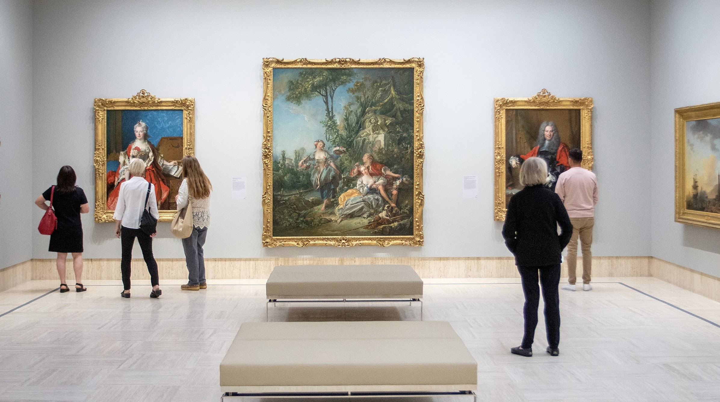 Two people holding hands and looking at a framed classical painting in a museum gallery.