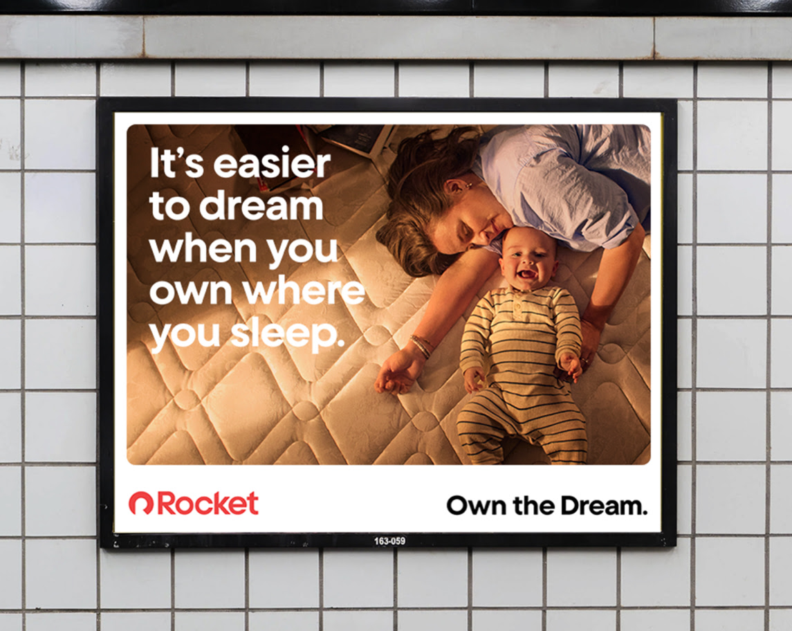 Subway ad: A woman and a smiling baby lying on a mattress. Text: "It's easier to dream when you own where you sleep. Rocket. Own the Dream."