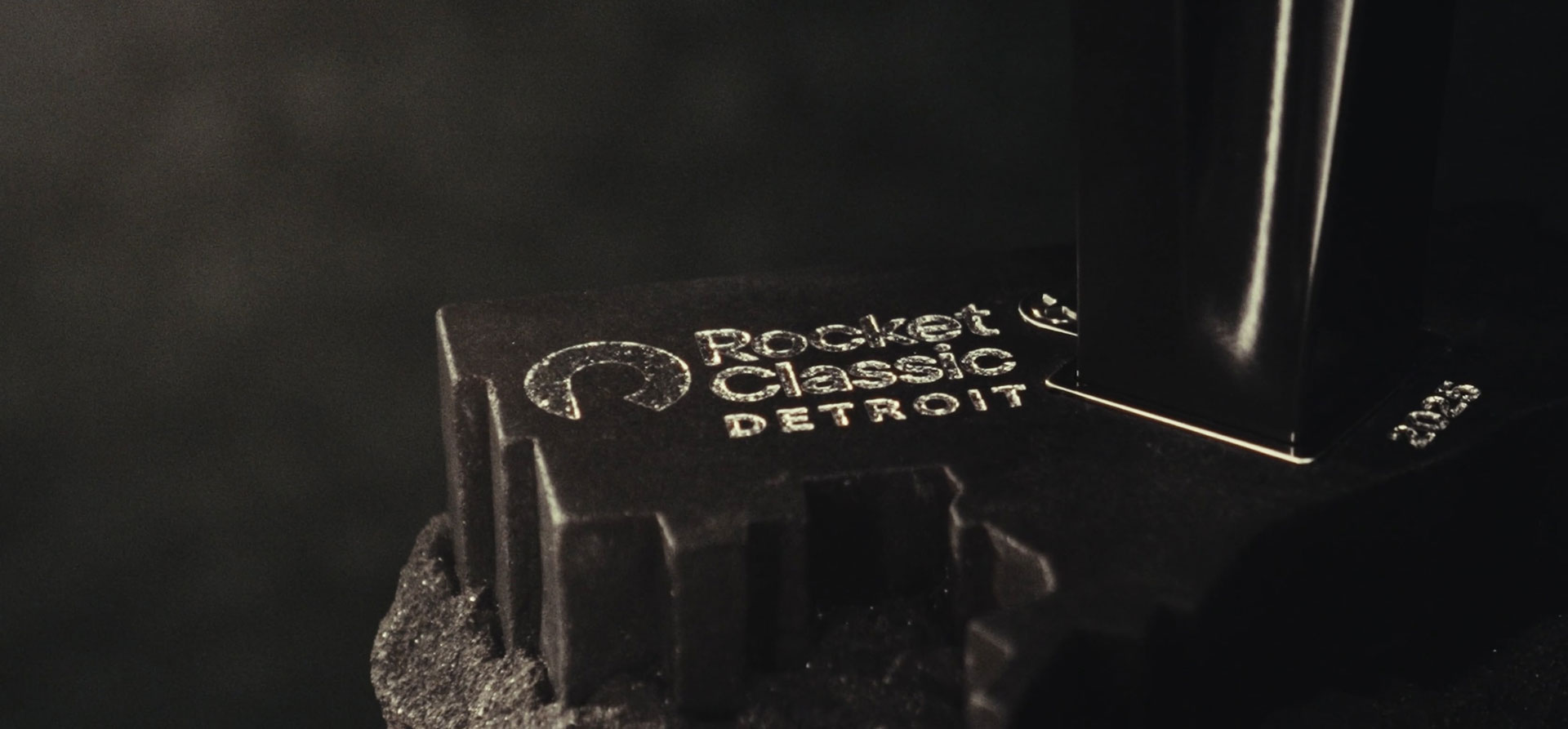 Close-up of a black trophy base engraved with the words “Rocket Classic Detroit” in silver text.
