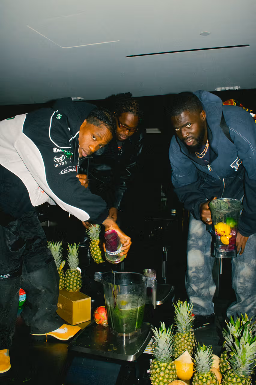 Three men blending smoothie ingredients including pineapple and dragon fruit for the Travis Scott x Erewhon Storm Smoothie collaboration campaign