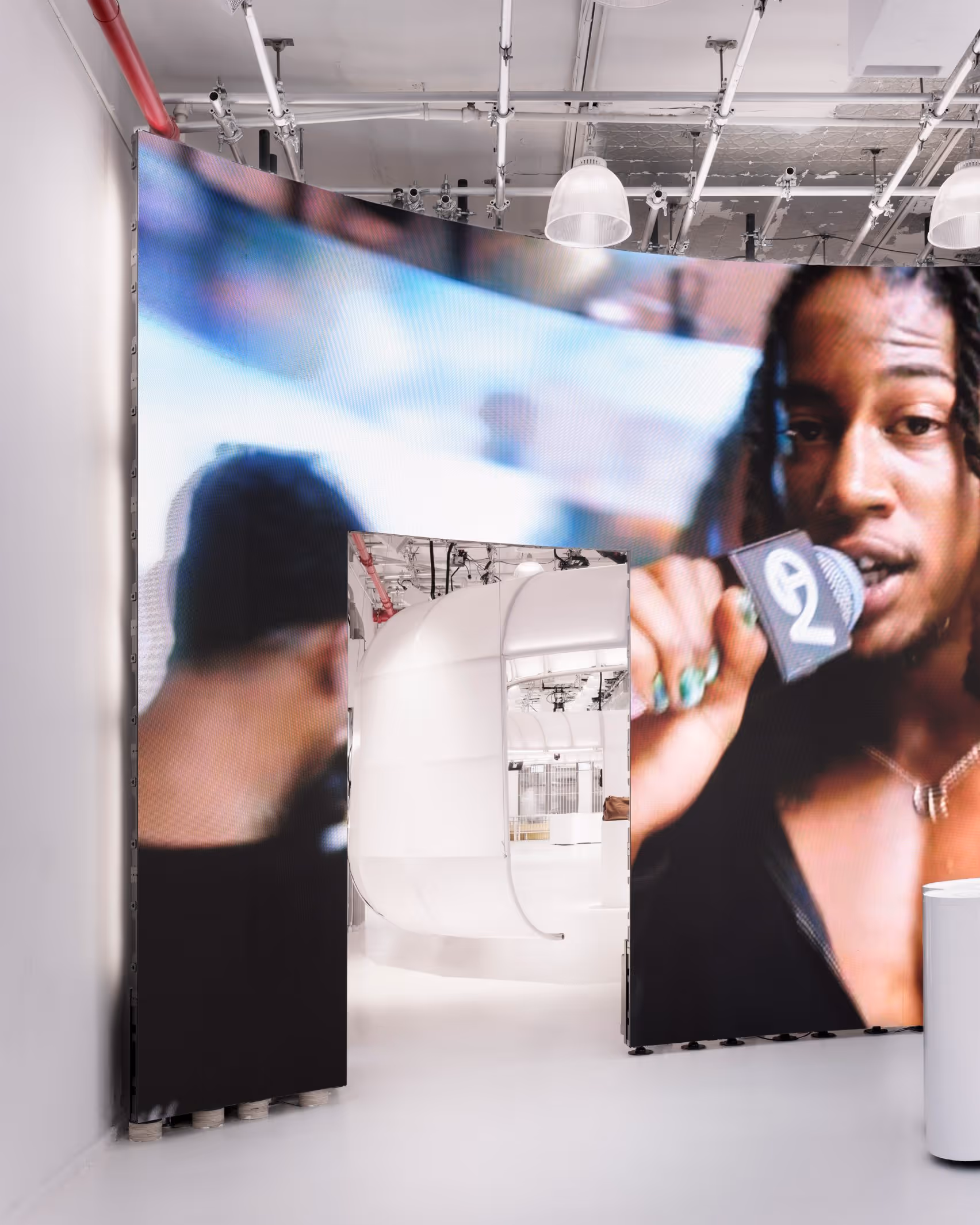 Large-scale LED video wall panels at the entrance of the Telfar flagship store displaying a close-up campaign portrait, with the white store interior visible through the gap between screens
