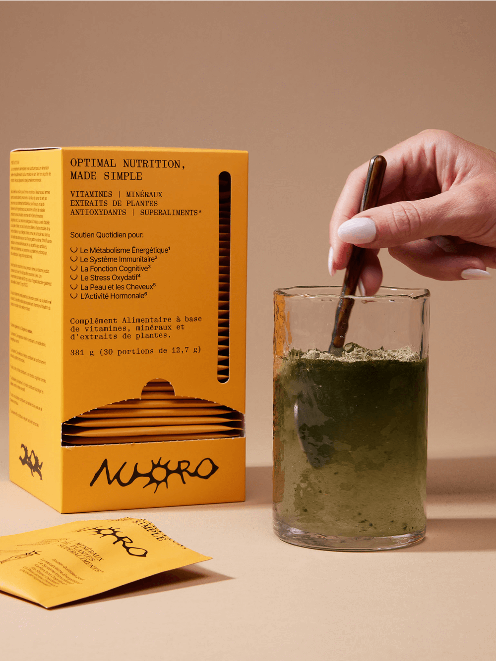 Nuoro supplement box and sachet alongside a glass being stirred with green powder, product photography for brand identity by Onmi Design