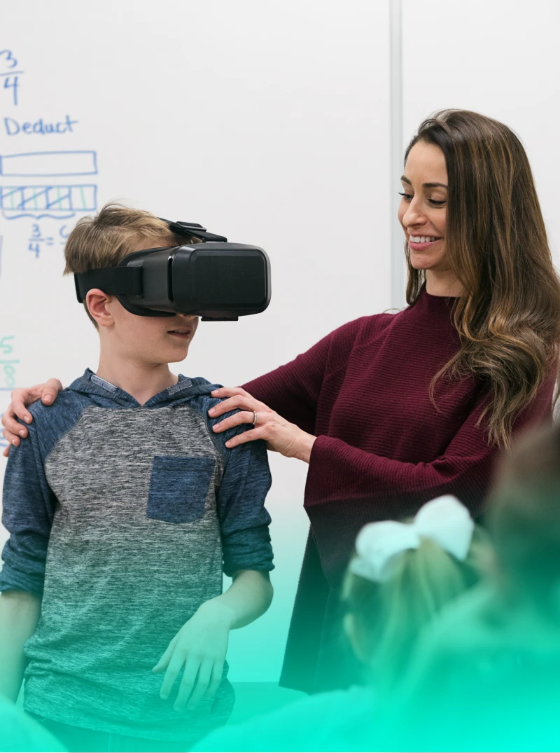 Teacher working with a student who is wearing VR goggles to learn.