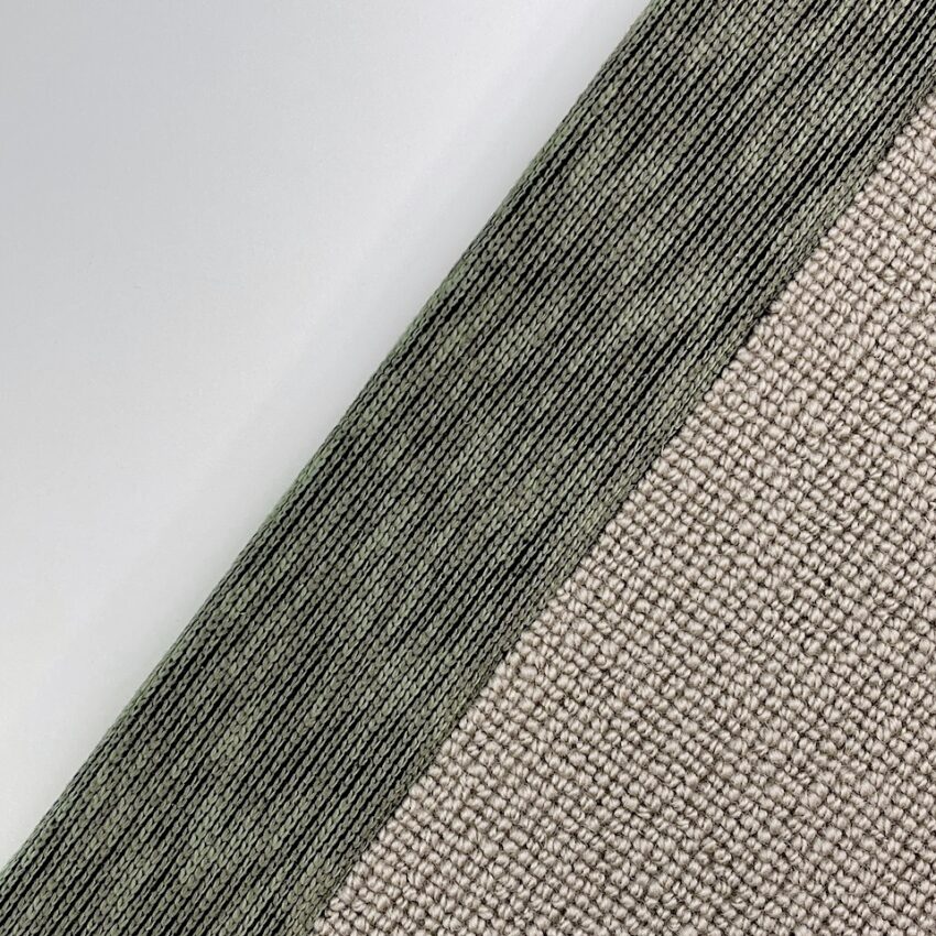 Close-up of textured beige fabric bordered by a woven green edging tape.