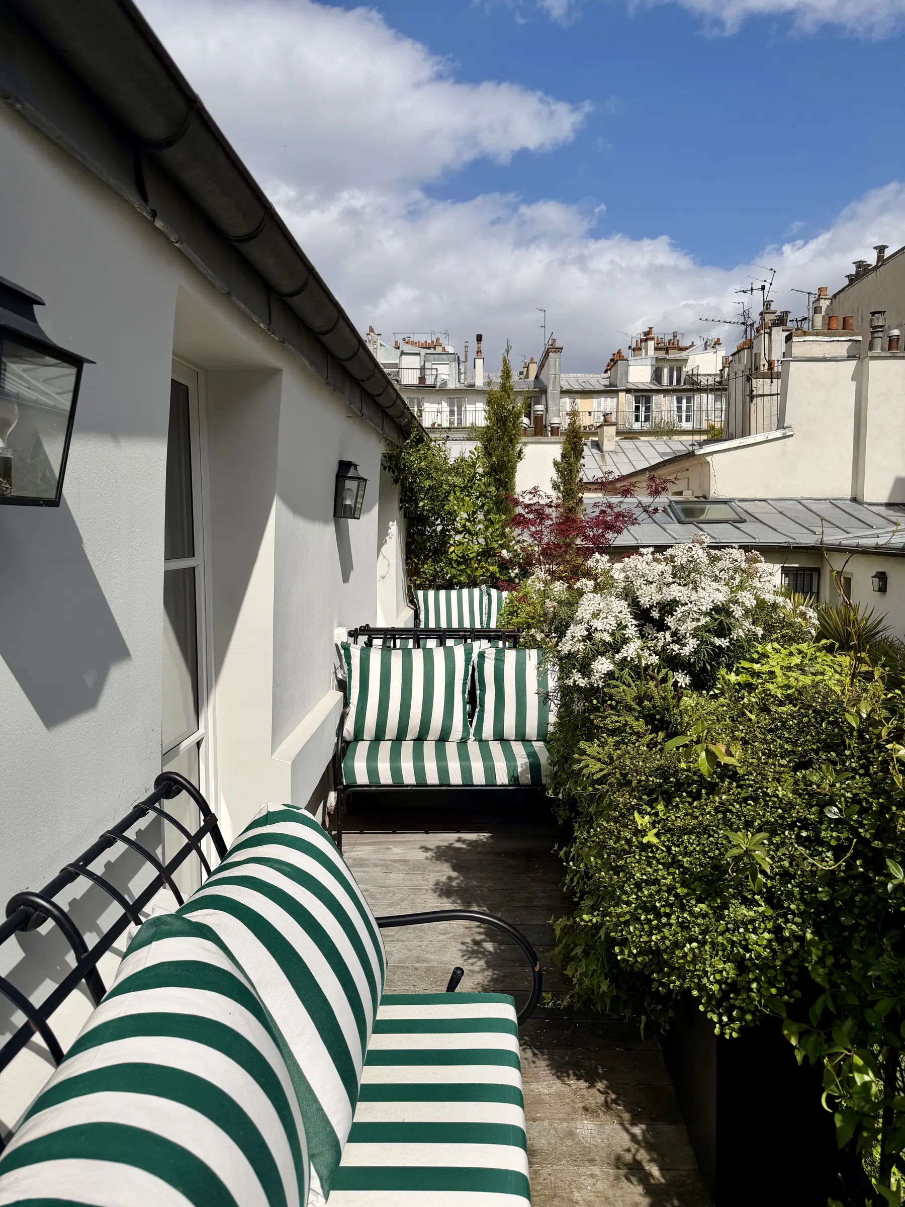 Terrasse sur les toits de Paris avec banquette rayée, appartement haussmannien rénové à Saint-Germain