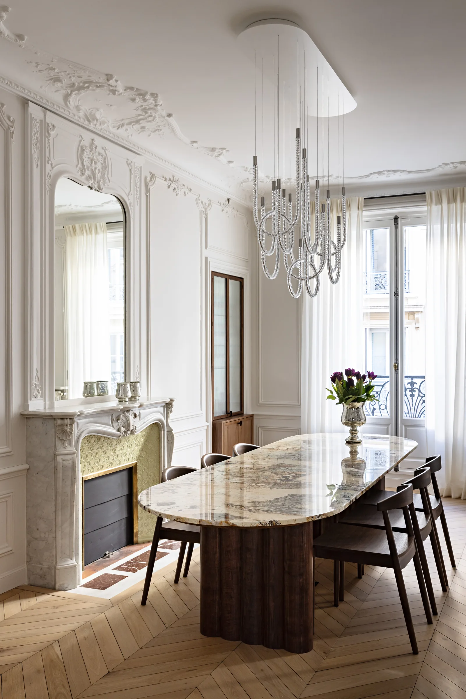 Salle à manger avec table en marbre, lustre et cheminée, appartement haussmannien rénové à Paris