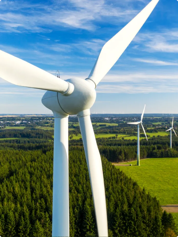 Aerial view of white wind turbines in a green field.