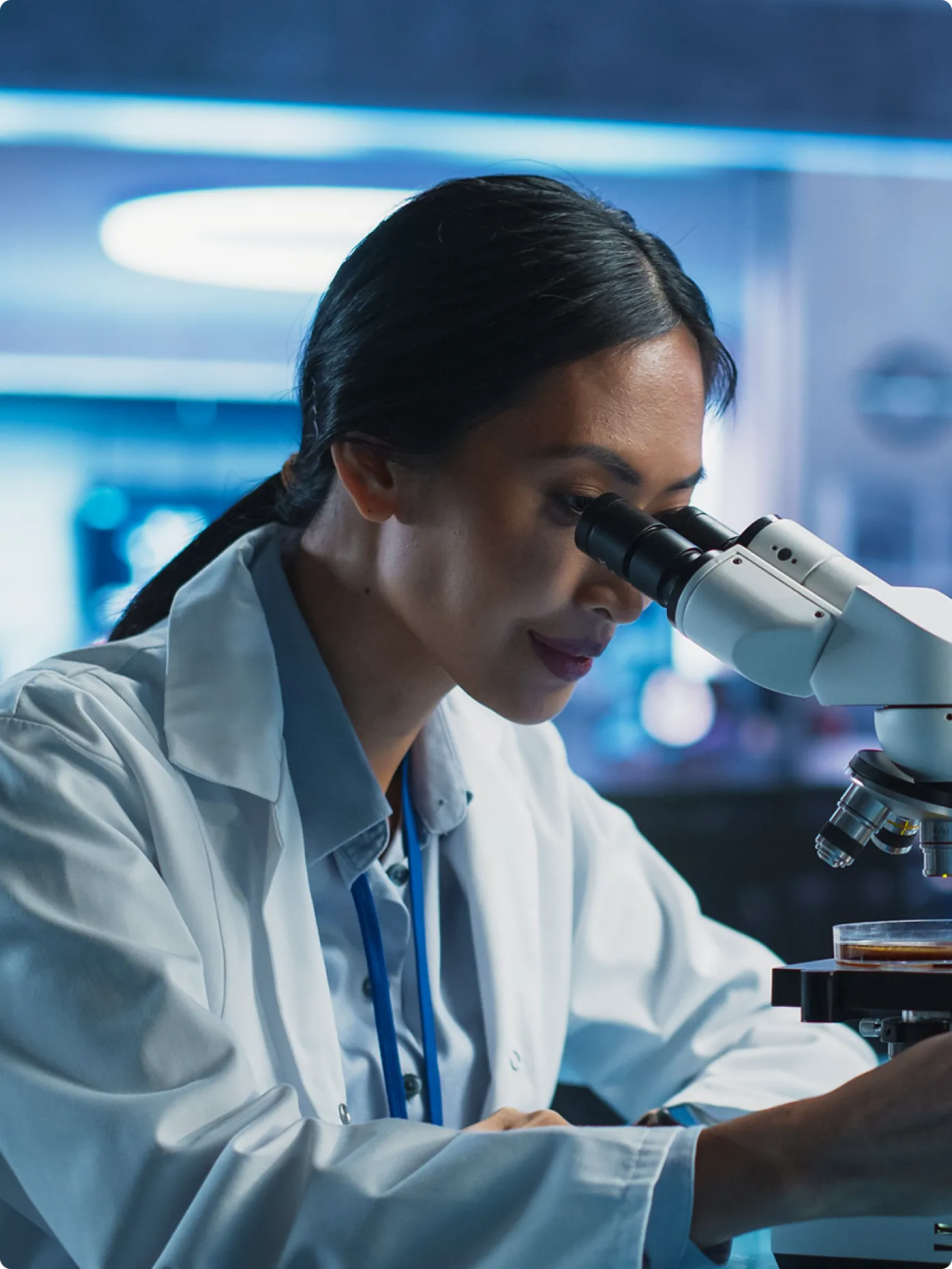 A doctor examines samples with a microscope in a lab.