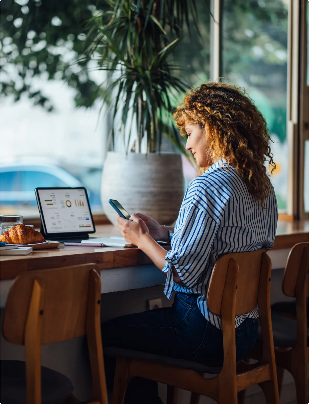 A woman sits at a table with a laptop open and a cup of coffee beside her, focused on her work.