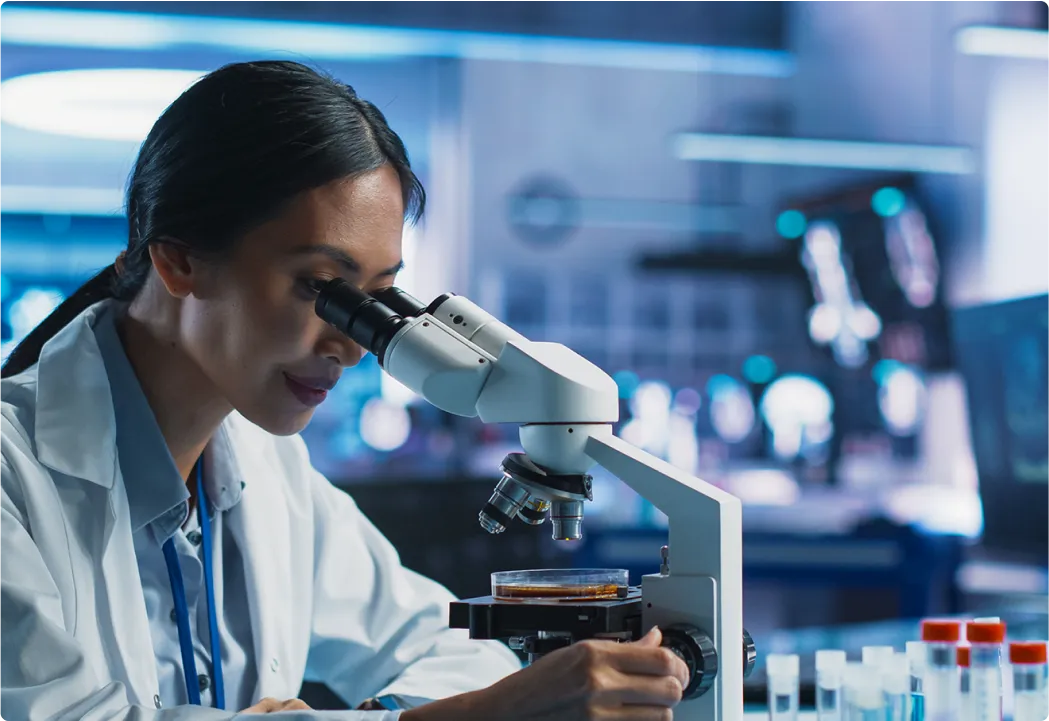 A doctor examines samples with a microscope in a lab.