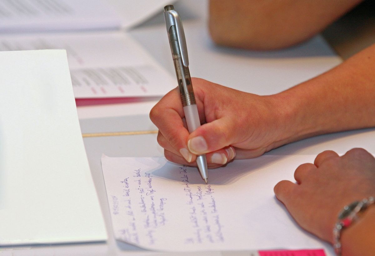 Frau schreibt mit Kugelschreiber auf einer Briefvorlage, Beispiel für handschriftliche Briefe und persönliche Kommunikation. Vorlage Briefe schreiben
