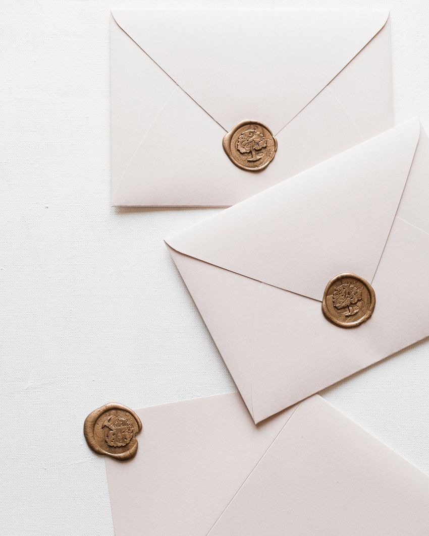 Elegante weiße Umschläge mit goldenen Wachs Siegeln, stilvolle Postsendungen mit individuell berechneten Briefporto.