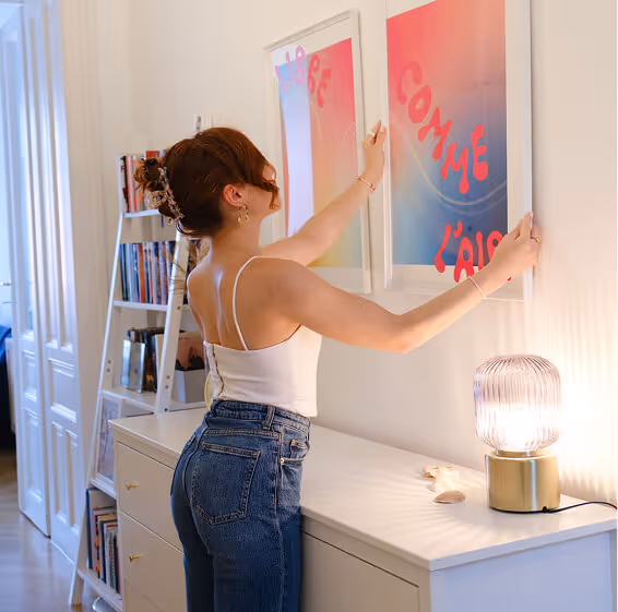 Catarina hängt eines ihrer Art Prints an die Wand in einer Wohnung.