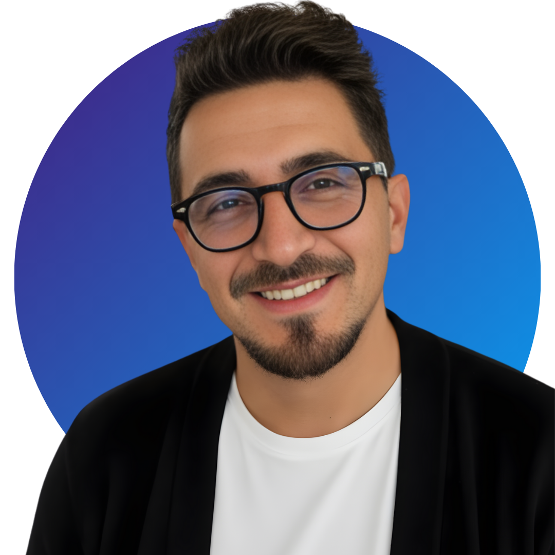 Ein Mann mit dunklen Haaren, Bart und schwarzer Brille lächelt vor einem blauen, runden Hintergrund.