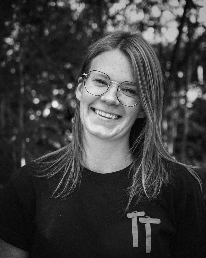 Black and white portrait of Rachael Morin. Trees behind.