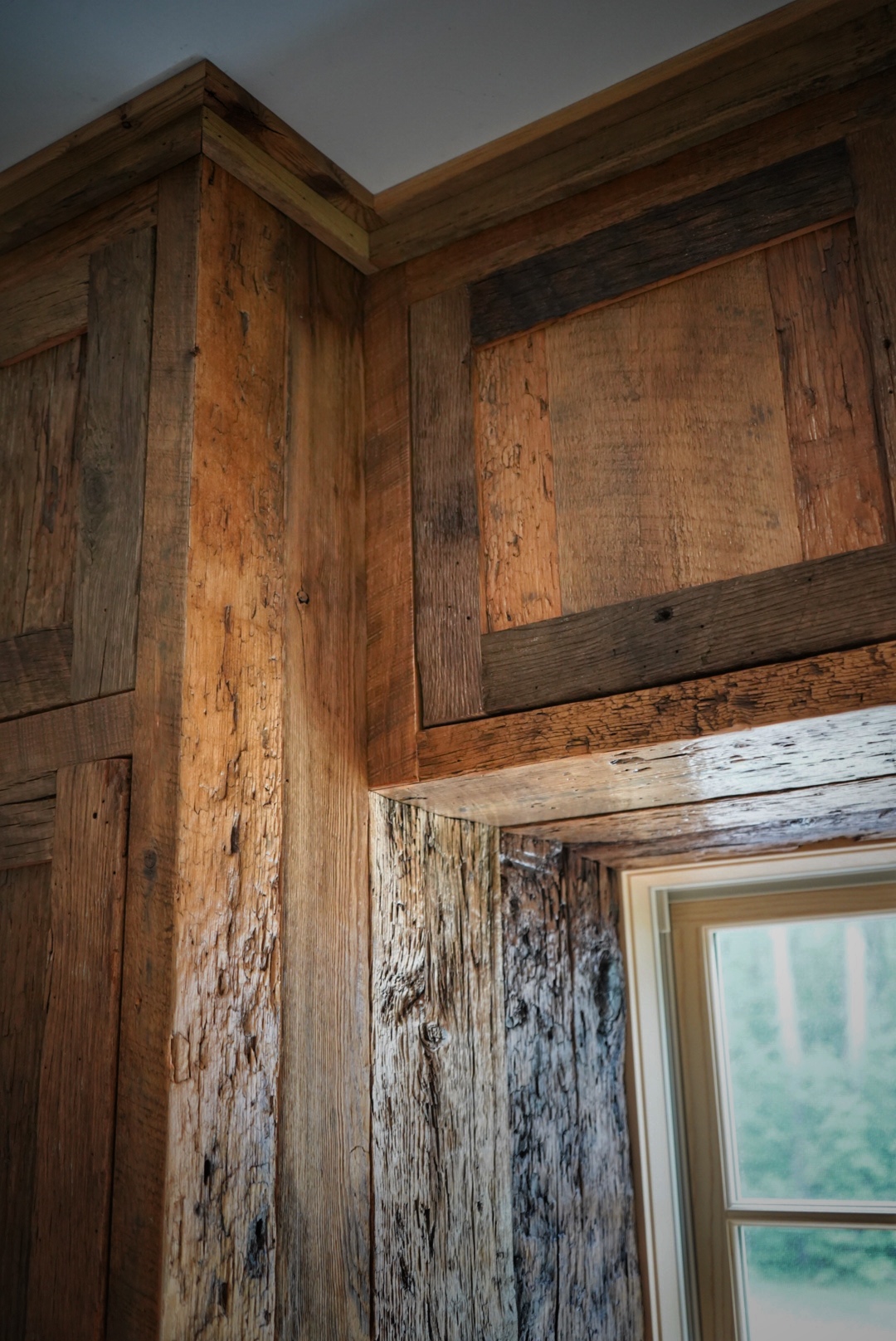 Project detail: Close up of top reclaimed cabinet around a window, from a lower angle looking up.