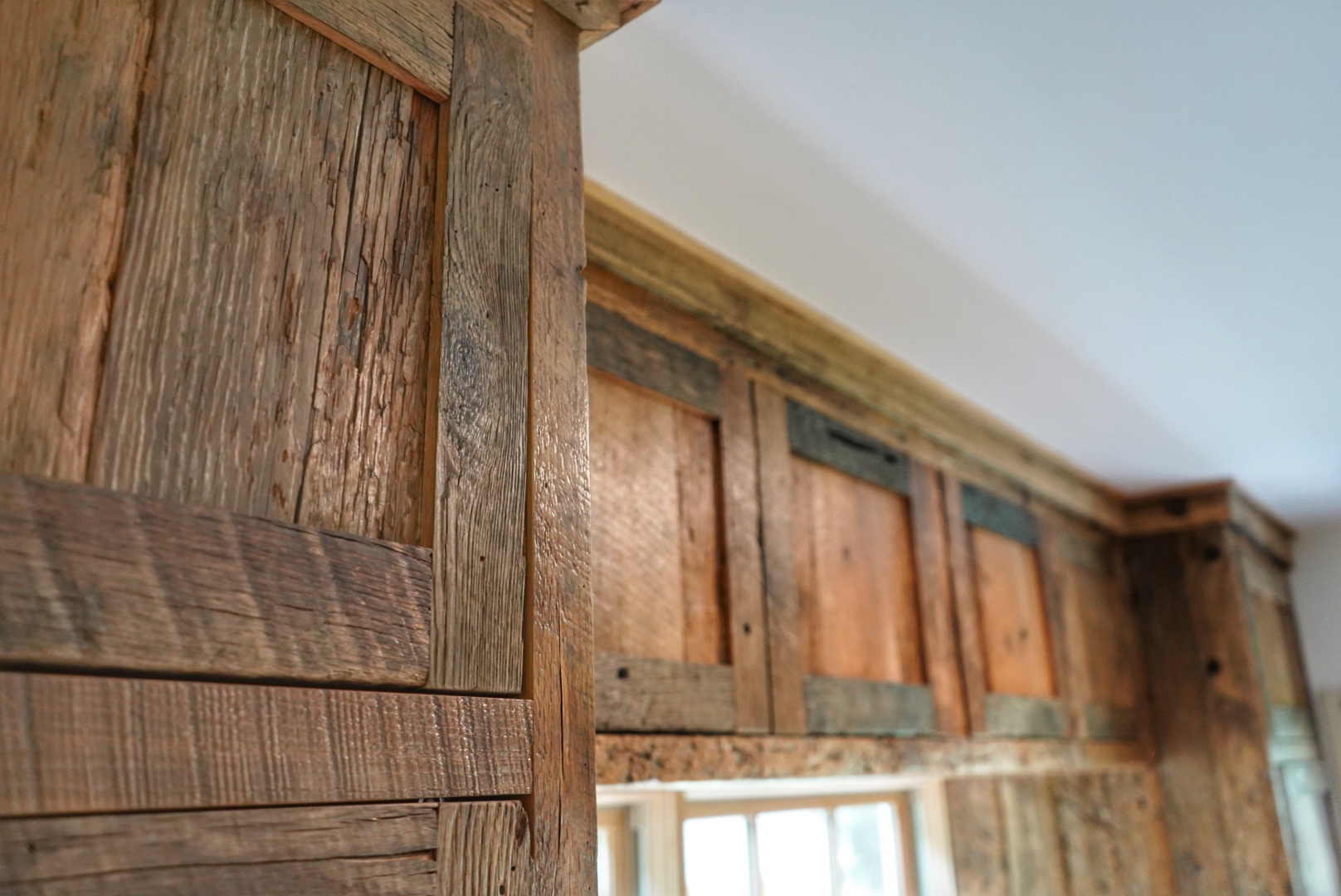Project detail: Top portion close up of reclaimed cabinetry around a window. 
