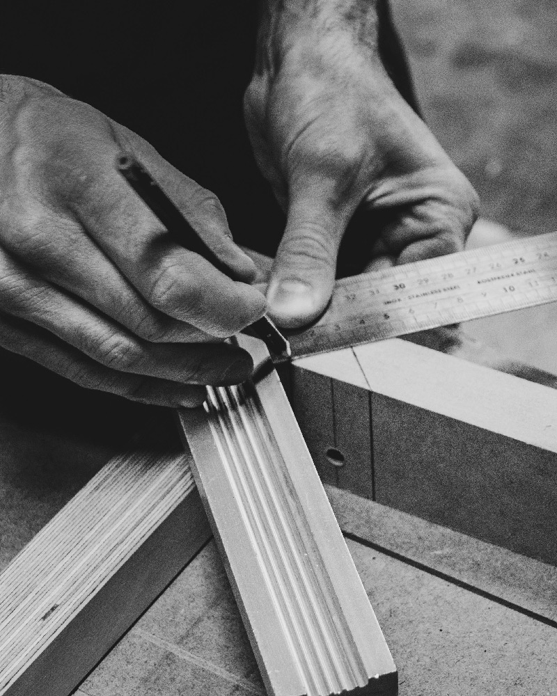 Close up, black and white image of a person measuring with a square.