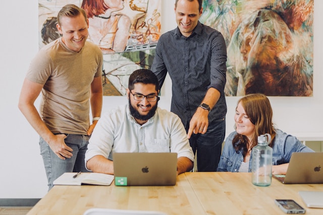 A group of people meeting and smiling looking at laptop screen