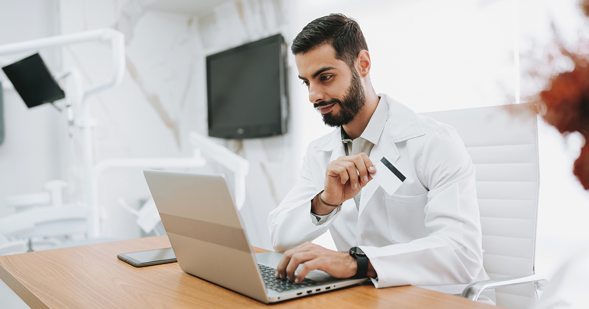 dental practice manager using credit card with laptop