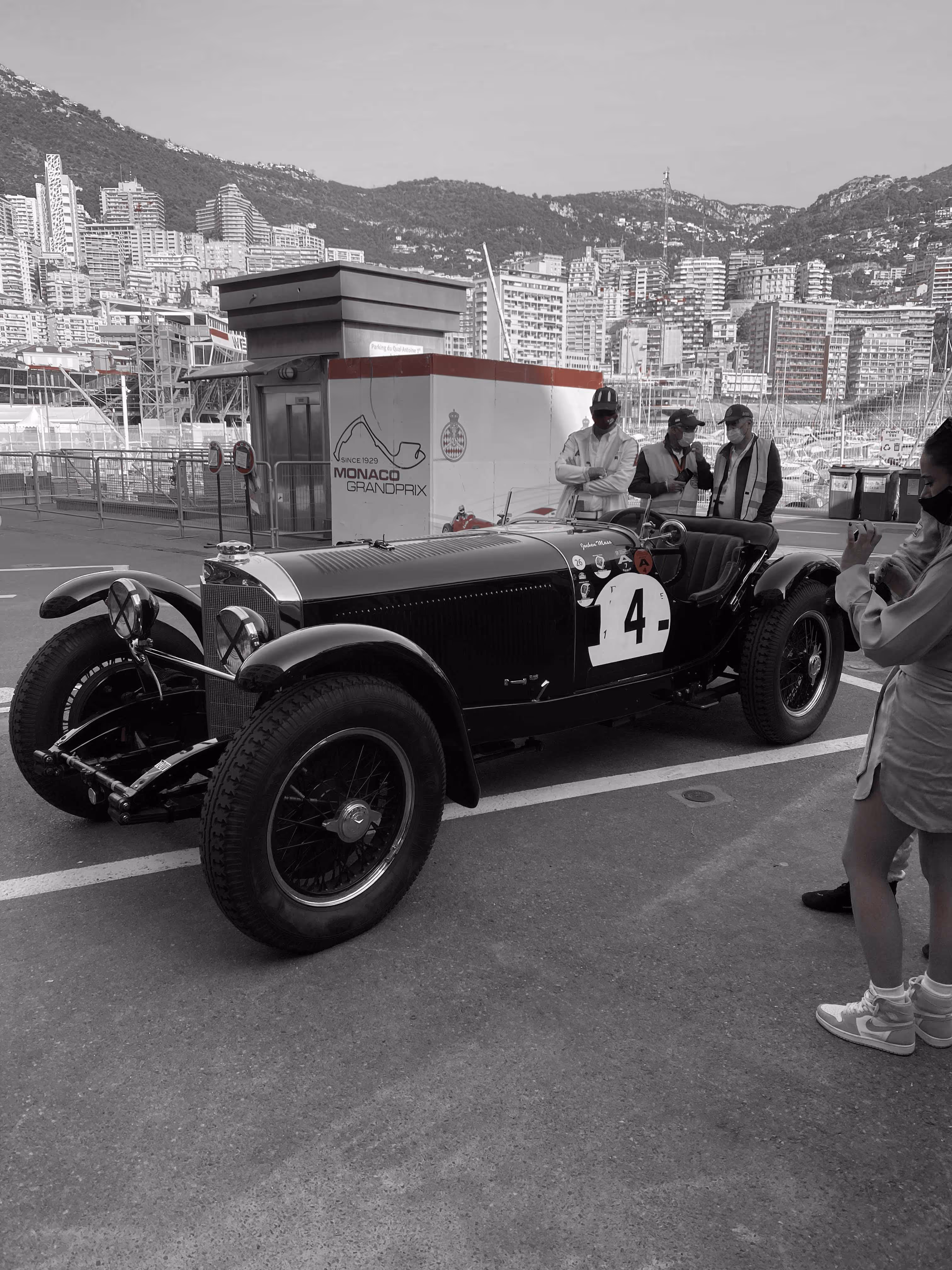 Vintage race car parked with Monaco skyline in background.
