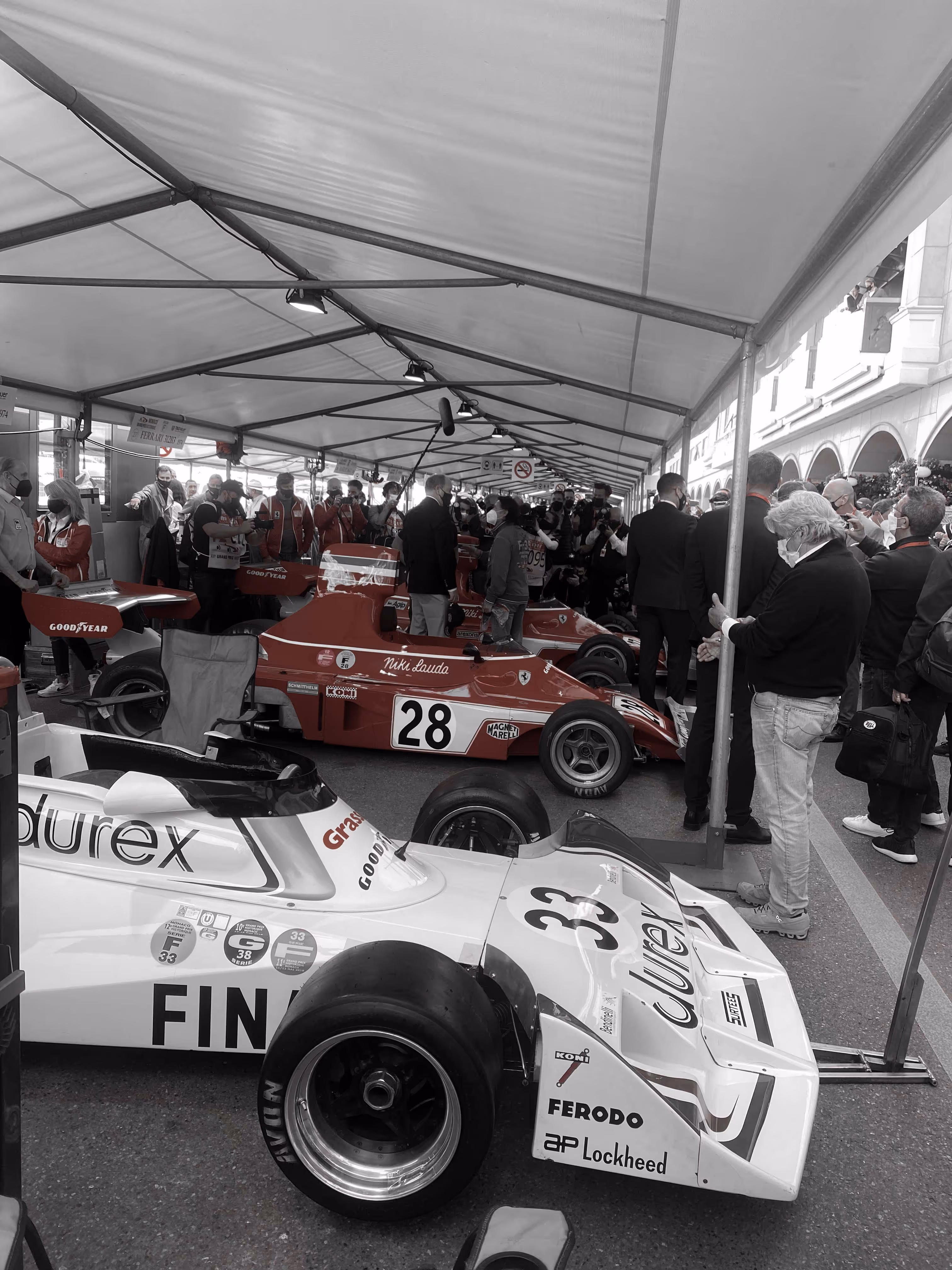Classic Formula One car under tent with spectators at Monaco Grand Prix Historique.