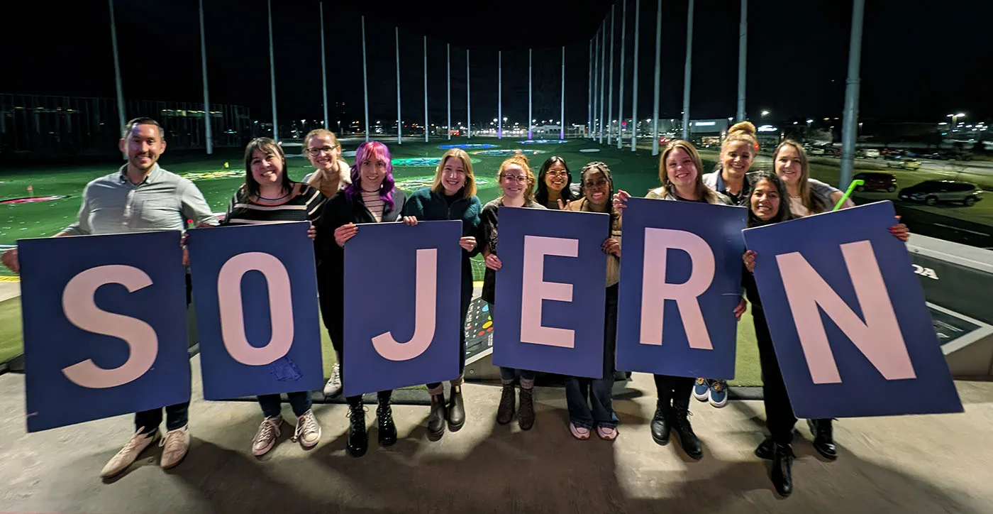 Team of people holding up letters that spell out the business name, Sojern.