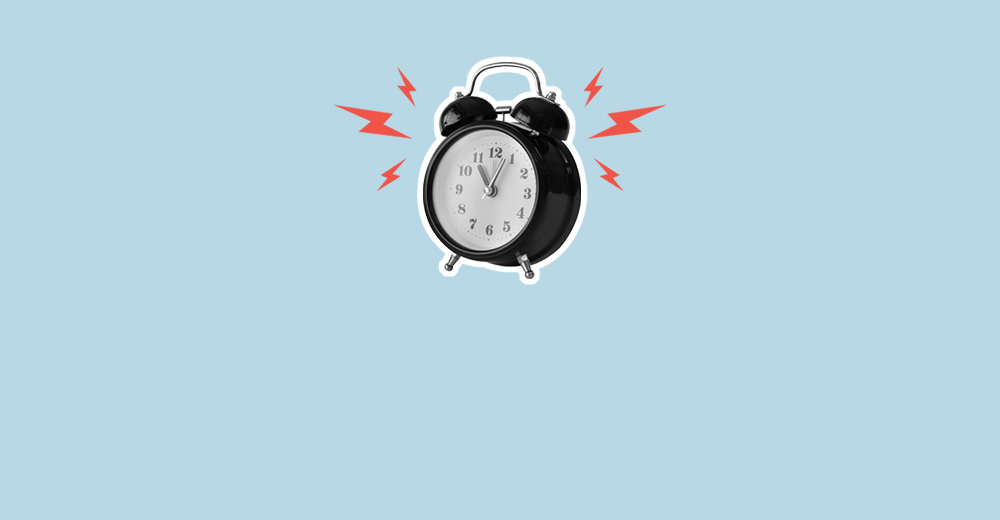 A hand holding an alarm clock